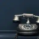 black and brown rotary phone near gray wall