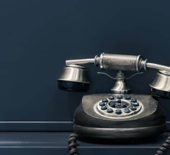 black and brown rotary phone near gray wall