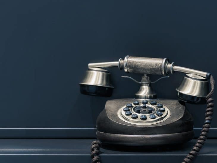 black and brown rotary phone near gray wall