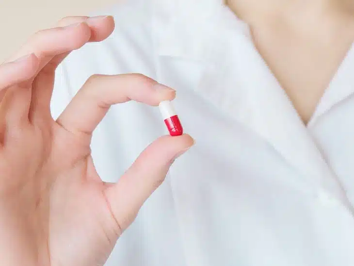 Crop nurse demonstrating small double colored pill